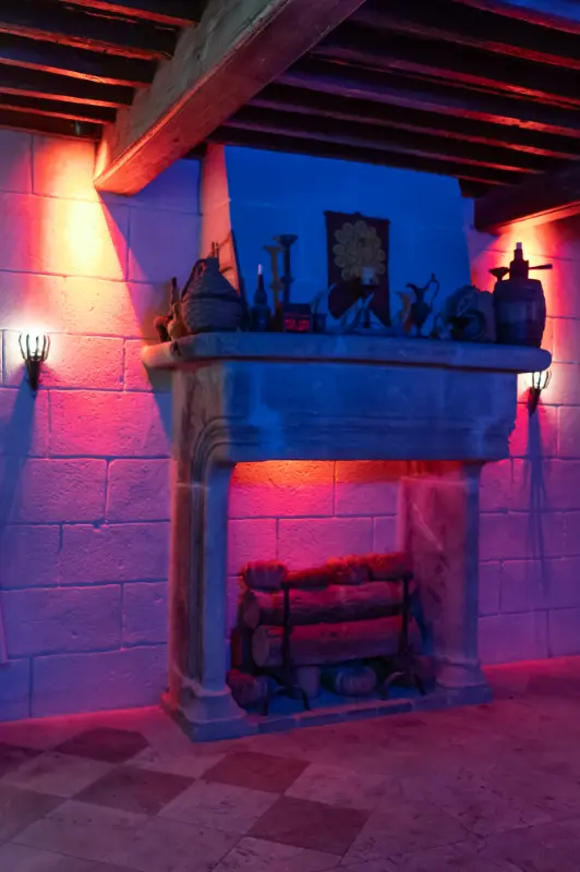 Gros plan sur la cheminée de la Taverne avec un éclairage violet/rouge