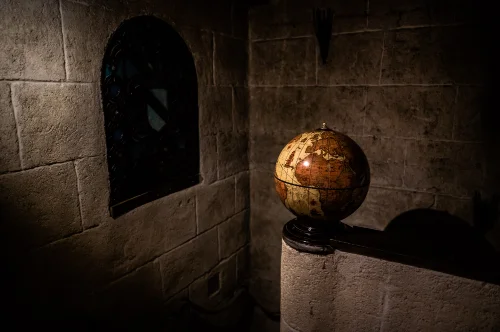 Un globe ancien en haut d'un escalier à côté d'un vitrail