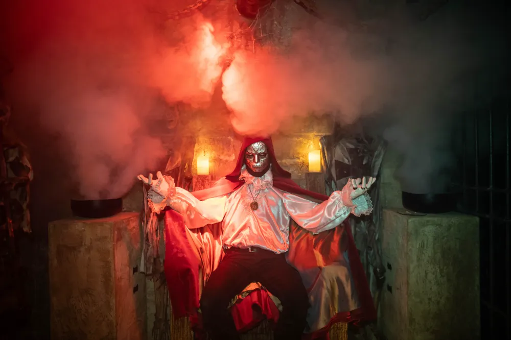 Masked figure with outstretched arms in red smoke