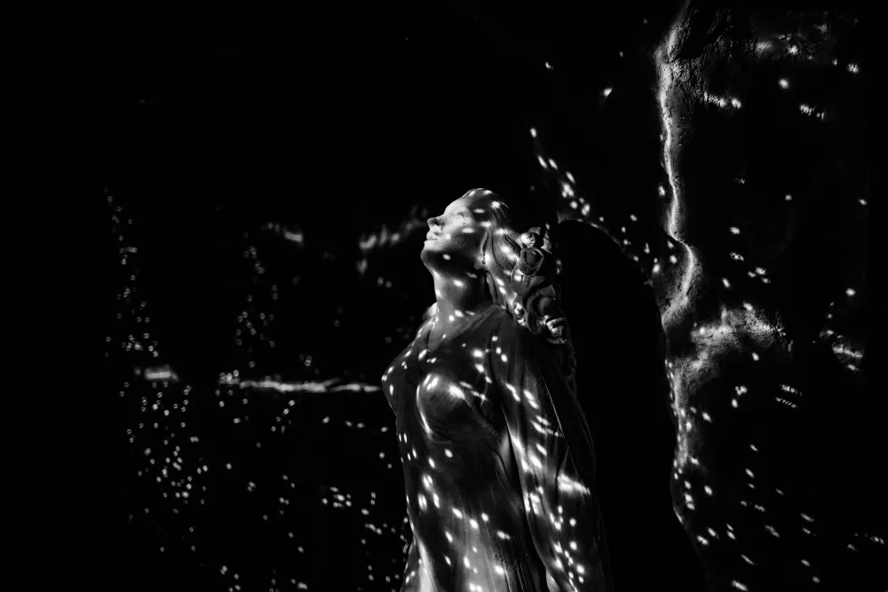 Statue de Léa parsemée d’éclats de lumière magique, dans l’obscurité